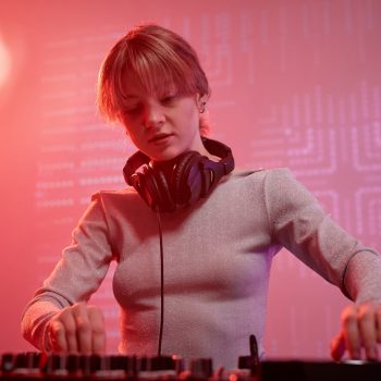 Portrait of young woman as female DJ Portrait of young woman as female DJ making music tracks at disco party in neon light